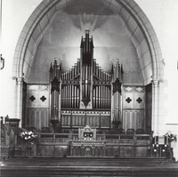 Image: a large church organ under a pointed stone arch