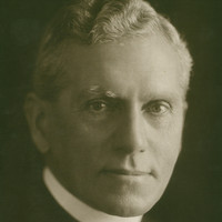 Image: Photographic head-and-shoulders portrait of a middle-aged, clean-shaven Caucasian man in an Anglican reverend's attire
