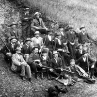 Image: Group of rifle club members sitting together on a hill holding rifles