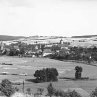 Image: A panoramic view of a German town. There are many houses. A number of large, open fields surround the town