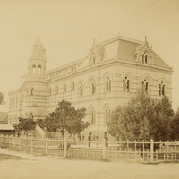 Image: Yellow-toned photograph of a large building with a turret