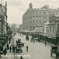 Image: City buildings and sparse horse-drawn traffic in Rundle Street, taken from an elevated position. Dominating the image is a huge five storey hotel building with a cupola on the corner of its roof. 