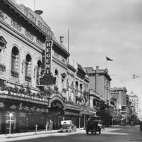 Image: a very ornate theatre building with plants hanging from and on top of its verandah as well as in window boxes on the second storey.