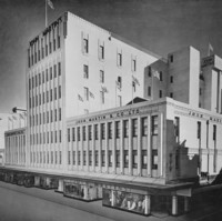 Image: a large 1930s era department store building with displays in its ground floor windows. The majority of the building is three storeys high, however, a seven storey tower protrudes from its centre. 
