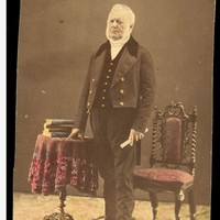 Image: coloured image of man standing next to chair and books