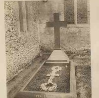 Image: Photograph of cross shaped headstone beside a church