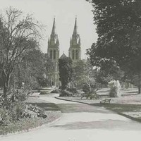 Image: Black and white photograph of a path winding through gardens towards a cathedral 