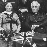 Group of women sitting down in foreground with flag, women standing in background