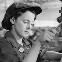 Image: A young woman uses a drill press to manufacture holes in a sheet of metal