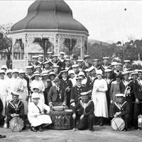 Men in naval uniforms plus the Burra girls and dignitaries group together for a photo infront of the local rotunda