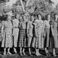 Image: Group of eight women standing in a line wearing long dresses