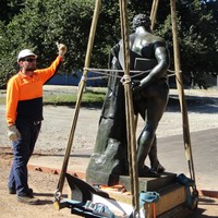 Image: man in hard hat and hi-vis supervising statue being lifted using hoist