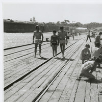 Image: People walking and others fishing with hand rods from a wooden jetty