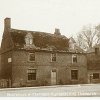 Birthplace of Matthew Flinders, Two storey brick house fronting a dirt road There is a window on either side of the front door, three upstairs windows, and two dormer windows in the roof, with slate roof. The house has since been demolished