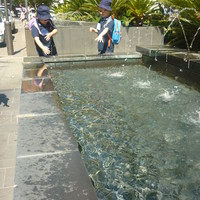 Two children standing next to a fountain