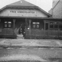 Image: two children standing in front of a cottage kindergarten