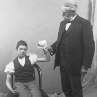 Image: seated boy with bandaged hand held by standing man