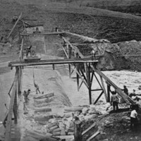 Image: Men working on structures over a flooding river