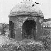 Black and white photo of concrete dome with arched entrances showing rocks inside