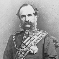 Image: A photographic portrait of a middle-aged Caucasian man in full military dress uniform. He has large mutton-chop sideburns and a bushy moustache