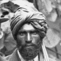 Image: Members of an exploring expedition pose for a photograph. An Afghan man with turban and western dress stands in the centre of the group