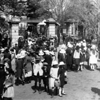 Image: crowd of children walking through large wrought iron gates