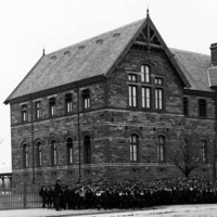 Image: large stone building with group of children in front