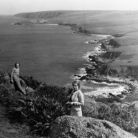 Image: Two women standing on rocks overlooking a rugged coastline