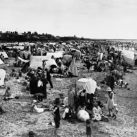 Image: Crowds of people on a beach with an assortment of tents
