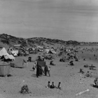 Image: People on a beach sheltering under umbrellas and tents