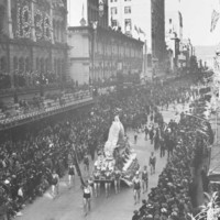 Image: parade of floral floats on street with crowds of people watching.