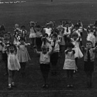 Image: large group of children on oval with arms stretched forwards