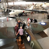 Image: group of planes in large hanger style building with people on platforms climbing into plane