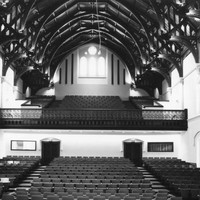 Image: The interior of a large hall with a hammerbeam roof and tiered seating on two levels.