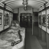 Image: The interior of a train carriage containing a railway model, and walls lined with information panels about railways