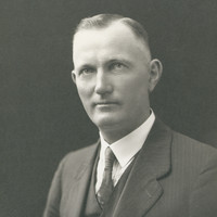 Image: Upper body portrait photograph of a man wearing a suit