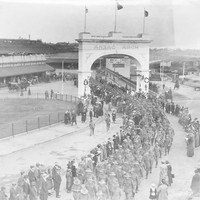 Image: Large group of men in uniform walking through arch and along path
