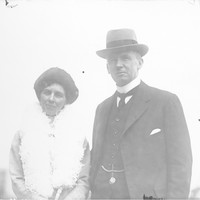 Image: man wearing hat and woman with boa pose for photograph
