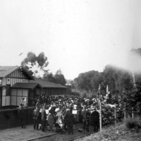 Image: group of people with flags gathered in front of building on railway tracks