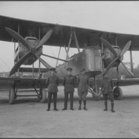 Image: Four men standing in front of a bi-plane
