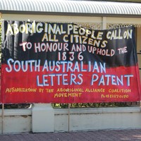 Image: large banner with message painted in yellow and white over a red and black background