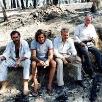 Image: four men sitting in burnt out bushland