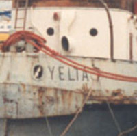Image: A derelict tugboat is moored against a wharf. A handful of other small boats are also moored at the same wharf