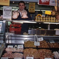 Image: man standing with large selection of raw chicken at market stall