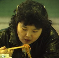Image: woman eating noodles with chopsticks