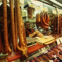 Image: man looking at sausages presented by woman at market stall