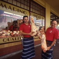 Image: two men holding meat in front of butchers shop