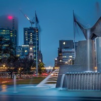 Image: Three Rivers Fountain which is located in Victoria Square, Adelaide.  This photo was taken at night time, with tall buildings in the background.