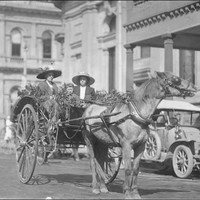 Image: Two women and a child sitting in a buggy drawn by a single horse through a city street