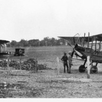 Image: bi-plane on ground with men standing nearby